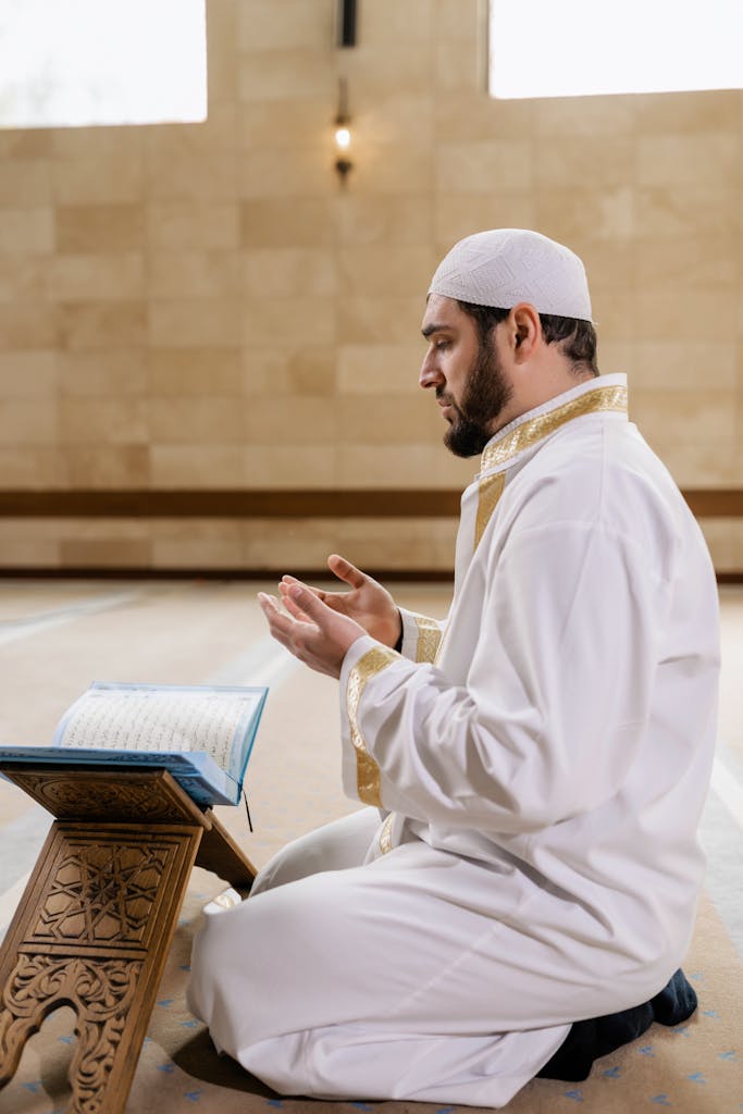 Man in White Thobe Sitting on the Floor Praying- الدعاء عند المرض؟