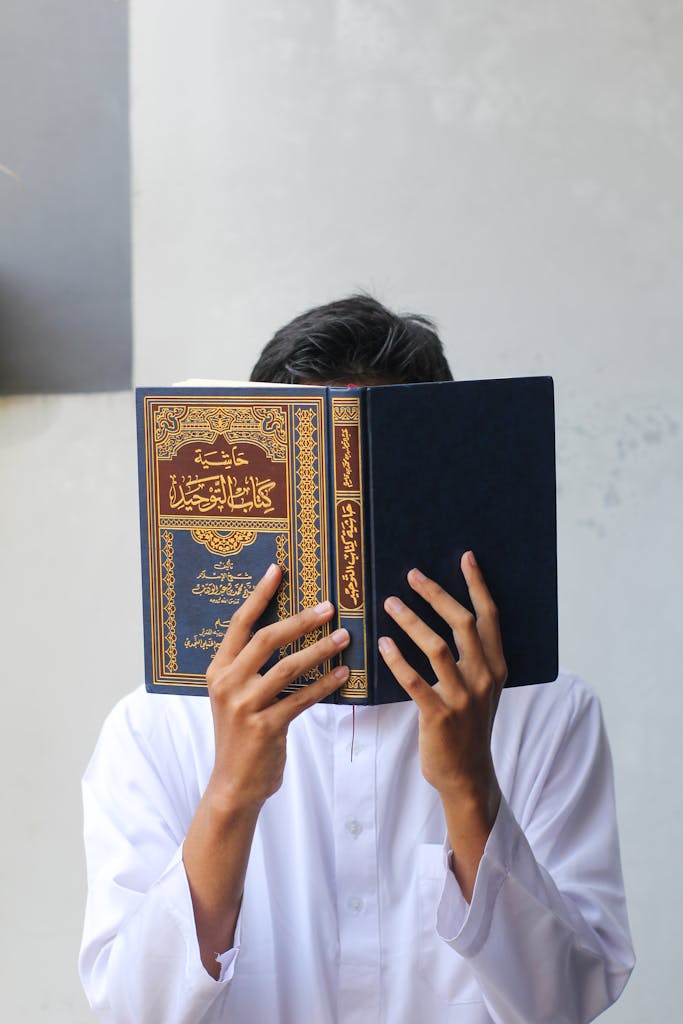 Person in White Long Sleeve Shirt Holding Blue Book